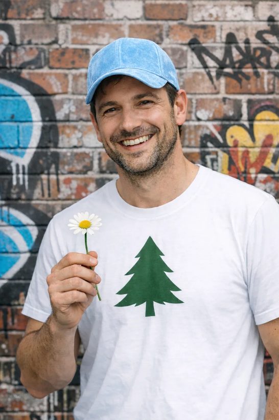 A man in a cap holding a small yellow flower